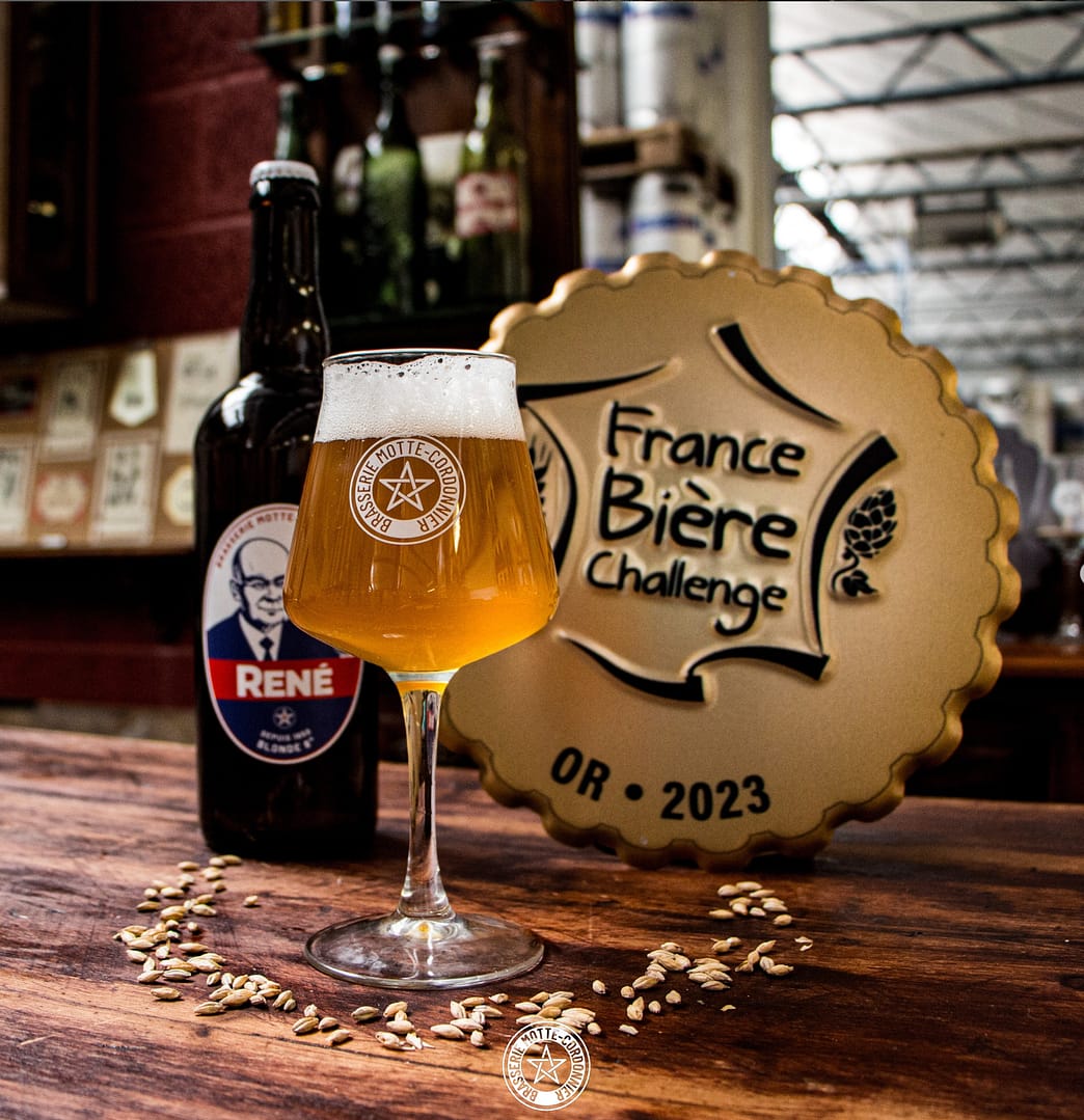 La bière René dans un verre accompagnée de sa médaille d'Argent. Brasserie Motte-Cordonnier